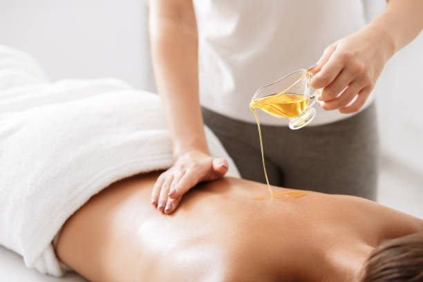 Spa treatment. Masseur pouring aroma oil on female back, doing massage